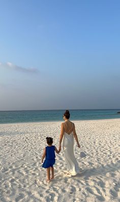 a woman and child are walking on the beach