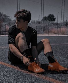 a young man sitting on the ground wearing orange shoes