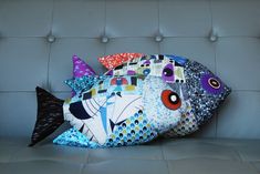 a colorful fish pillow sitting on top of a couch