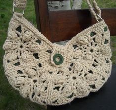 a crocheted purse sitting on top of a wooden bench