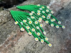 a green and white beaded necklace sitting on top of a rock