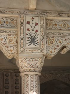 an intricately decorated pillar with flowers and leaves on it's sides, in the middle of a building