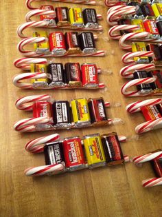 many candy canes and batteries are lined up on a wooden table with peppermint sticks