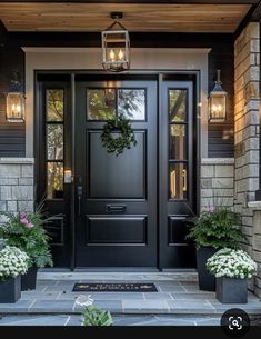 a black front door with two planters on each side and one light hanging from the ceiling