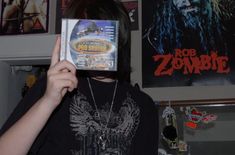 a person holding up a cd in front of their face with the word rob zombie on it