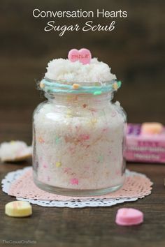 a small jar filled with pink and white sugar on top of a doily covered table