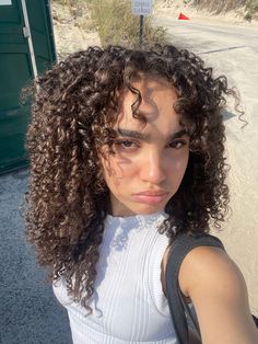 a woman with curly hair standing in the street