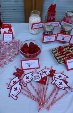 a table topped with lots of desserts and candies on top of a white table cloth