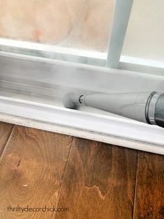 a close up of a window sealer on the side of a door with wood flooring