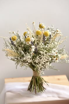 a vase filled with lots of white and yellow flowers