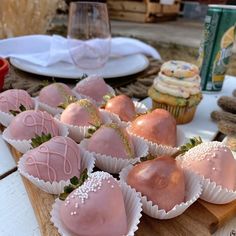 some chocolate covered strawberries are on a wooden board with other desserts in the background