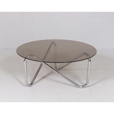 an oval glass table with metal legs on a white background in the style of knoll