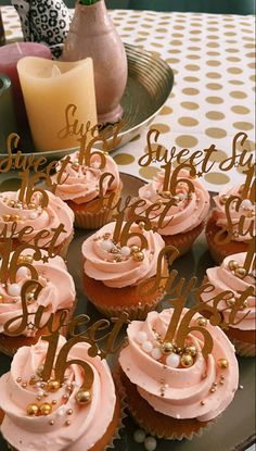 cupcakes with pink frosting and gold decorations on a plate that says sweet sixteen