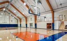 an indoor basketball court with blue and orange flooring