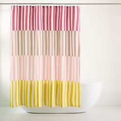 a shower curtain with multi colored stripes on it in front of a white bathtub