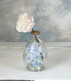 a white flower in a glass vase with blue flowers