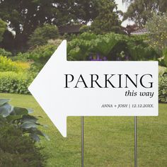 a white parking sign sitting on top of a lush green field