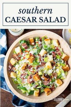 a salad with croutons and bacon in a wooden bowl on top of a table