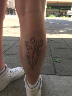 a woman's legs with tattoos on them and flowers drawn on the side of her leg