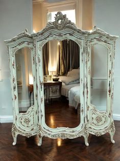 an ornate white dresser and mirror in a room with hardwood floors, walls and windows