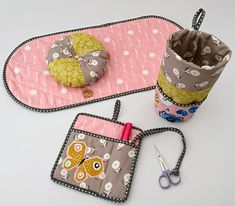 two pot holders with scissors and sewing supplies on them next to a pair of scissors