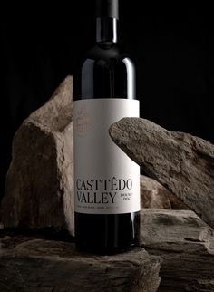 a bottle of red wine sitting on top of a wooden table next to some rocks