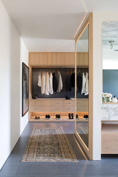 a walk in closet with clothes hanging on the wall and an area for shoes to be placed