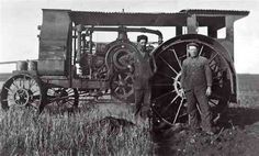 two men standing next to an old tractor