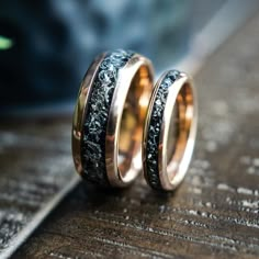 two gold wedding bands with black and white marble inlays on top of each other