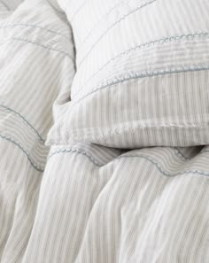 an unmade bed with white and blue striped pillows