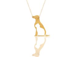 a gold necklace with a dog on it's neck and reflection in the water