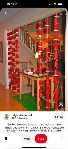 a room filled with lots of red cups on top of a wooden table next to a stair case