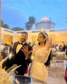 a man and woman in formal wear standing next to each other at a wedding reception