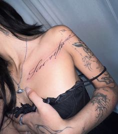 a woman with tattoos on her chest and arm holding a cell phone in her hand