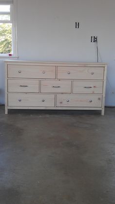 a white dresser sitting in the middle of a room with two clocks on it's wall