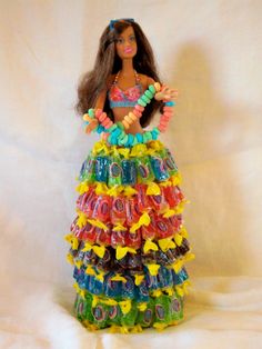 a barbie doll wearing a colorful dress made out of plastic beads and bracelets on a white background