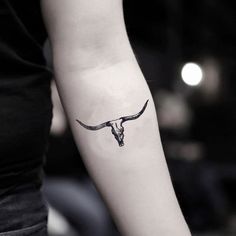 a woman's arm with a cow skull tattoo on the left side of her arm