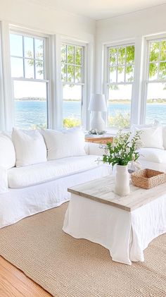 a living room with white furniture and large windows overlooking the water on a sunny day