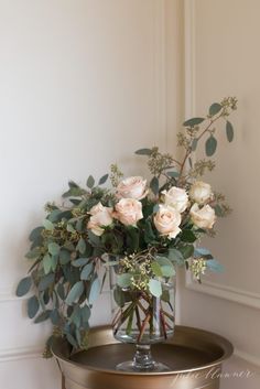 a vase filled with flowers sitting on top of a metal tray next to a wall