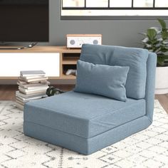 a blue chair sitting on top of a rug in front of a tv