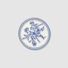 a blue and white plate with flowers in the middle on a grey background, there is no image here to provide a caption for