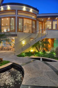 a large house with a fountain in front of it at night, lit up by lights