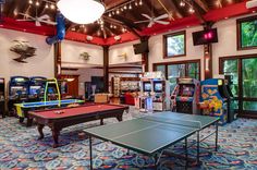 an indoor recreation room with ping pong tables, arcade machines and video game systems