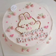 a birthday cake decorated with pink and white frosting, topped with an easter bunny