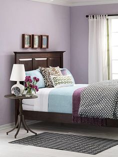 a bed room with a neatly made bed and purple walls