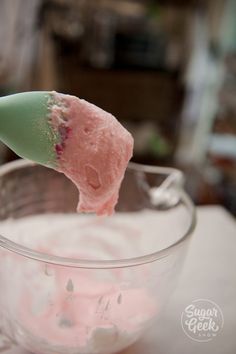 a spoon with some food in it on top of a glass bowl filled with liquid