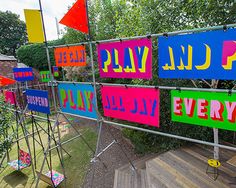 there are many colorful signs on the wall outside in the yard that says play day every