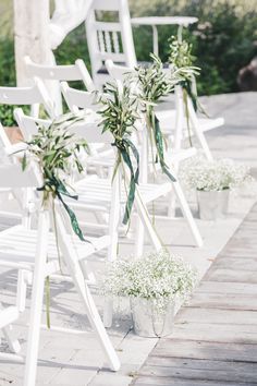 white chairs lined up with baby's breath flowers and greenery tied to them