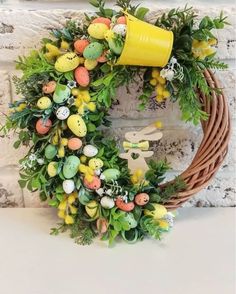 an easter wreath with eggs, carrots and greenery on a white brick wall