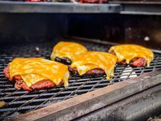 three hamburger patties cooking on a grill with cheese and sauce over them, ready to be cooked